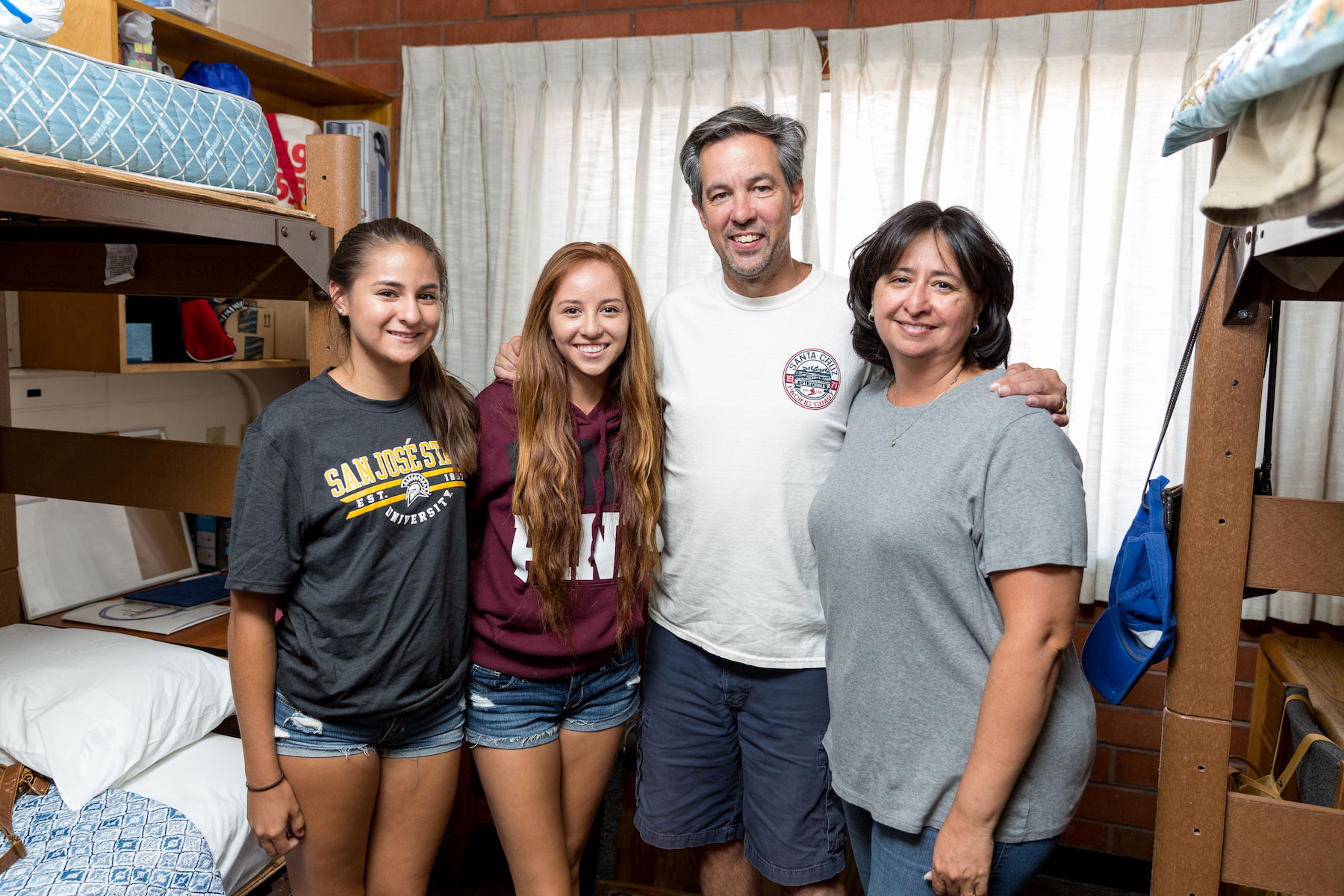 Freshman students posing with their parents in the dorm.