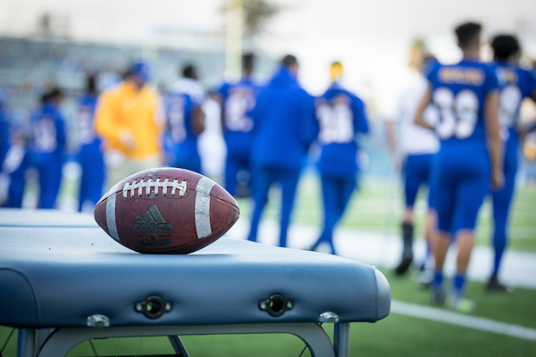 Football in focus on a bench with players in the background