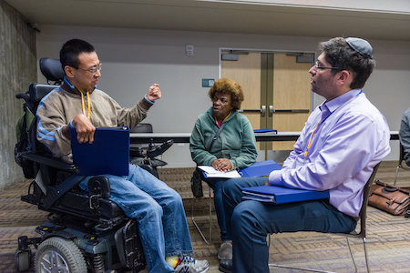 Three people deep in dialogue, one geturing with his hand.