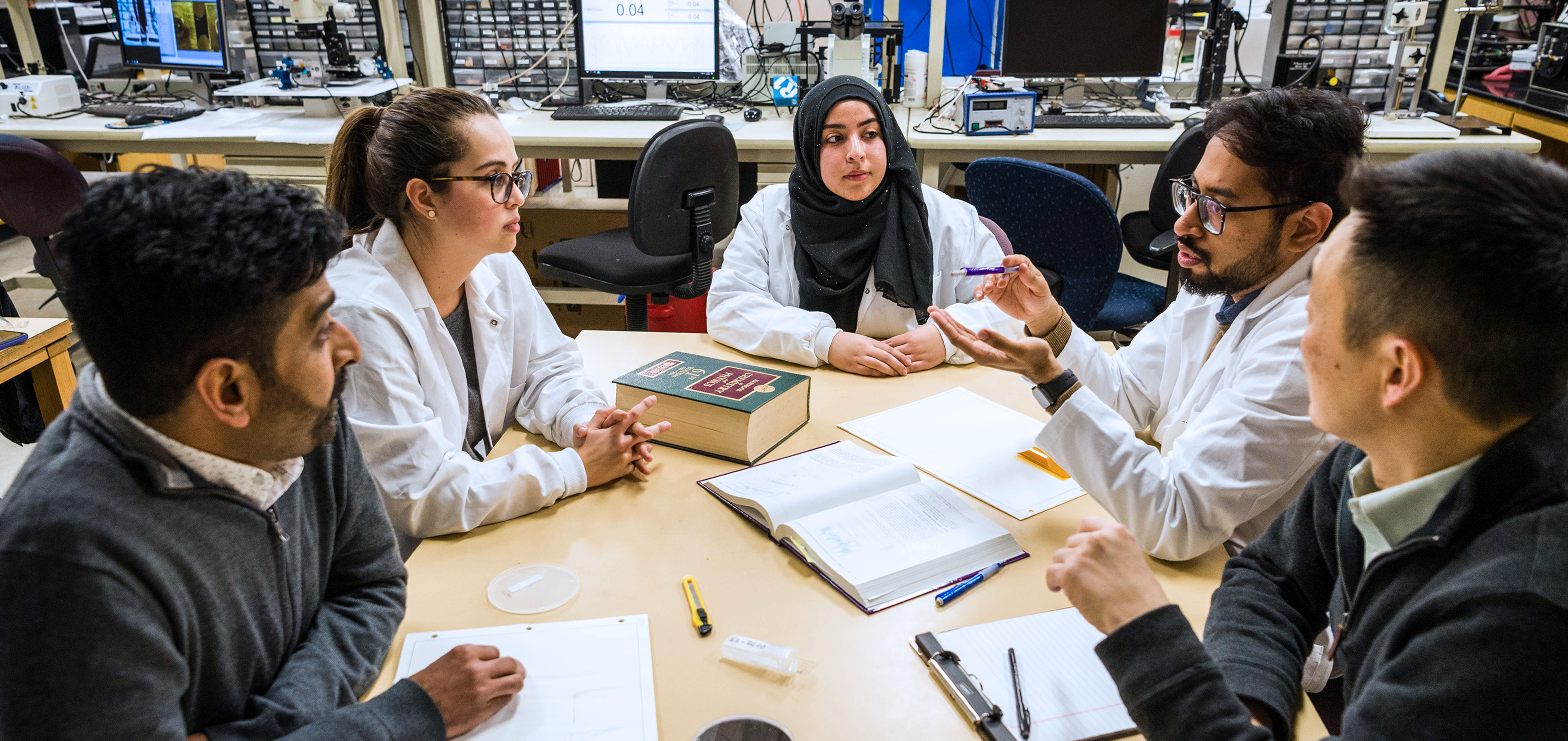 SJSU researchers are gathered around a table while discussing work.