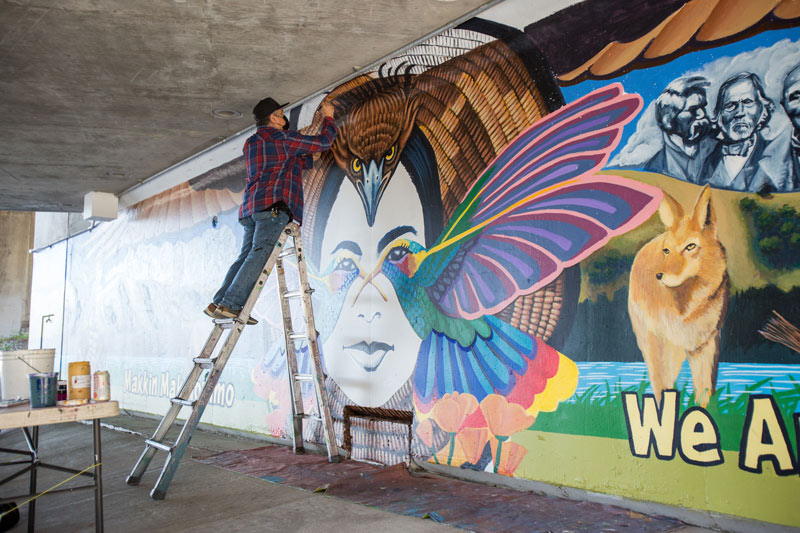 Alfonso Salazar on a ladder painting his mural.