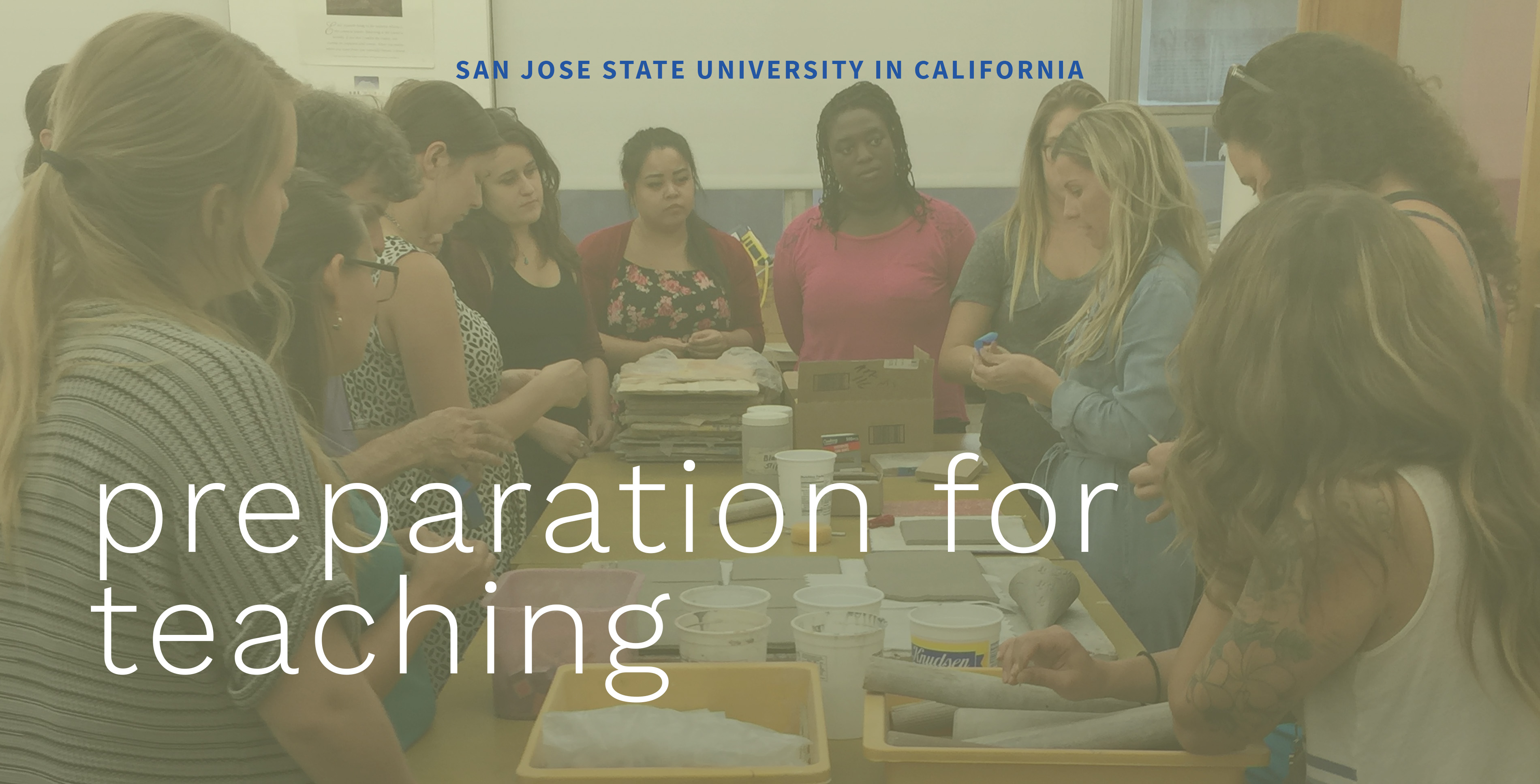 Photo of a class of students around a table working with clay.